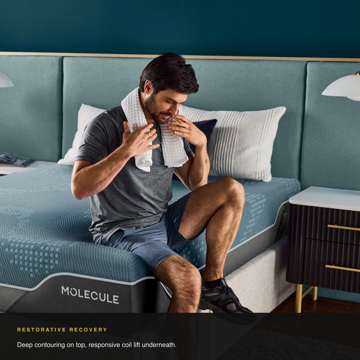 Man sitting on the edge of the MOLECULE Reflex Elite Hybrid 14 mattress after a workout