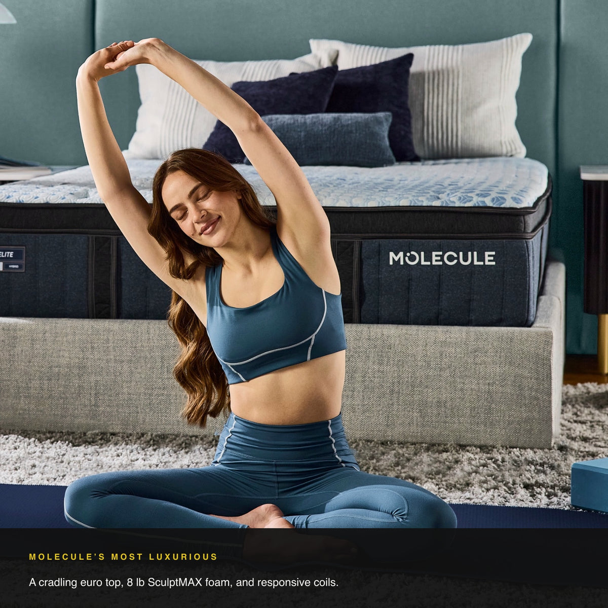 Woman stretching on the MOLECULE Engage Elite Hybrid 14 mattress in a bedroom